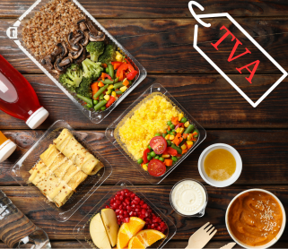 Plateaux repas et boissons à emporter disposés sur une table en bois, avec une étiquette illustrée portant la mention “TVA”.