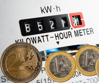 Compteur électrique affichant des kilowattheures avec des pièces en euros au premier plan, symbolisant le coût de l’énergie.